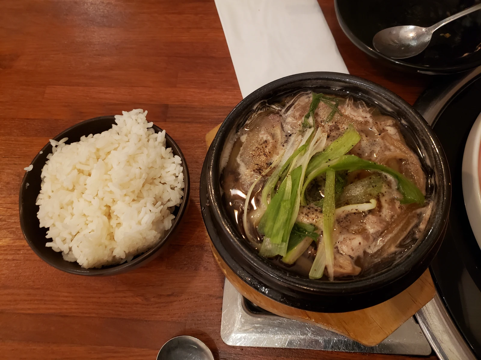 Brothy bulgogi in an earthenware pot beside rice