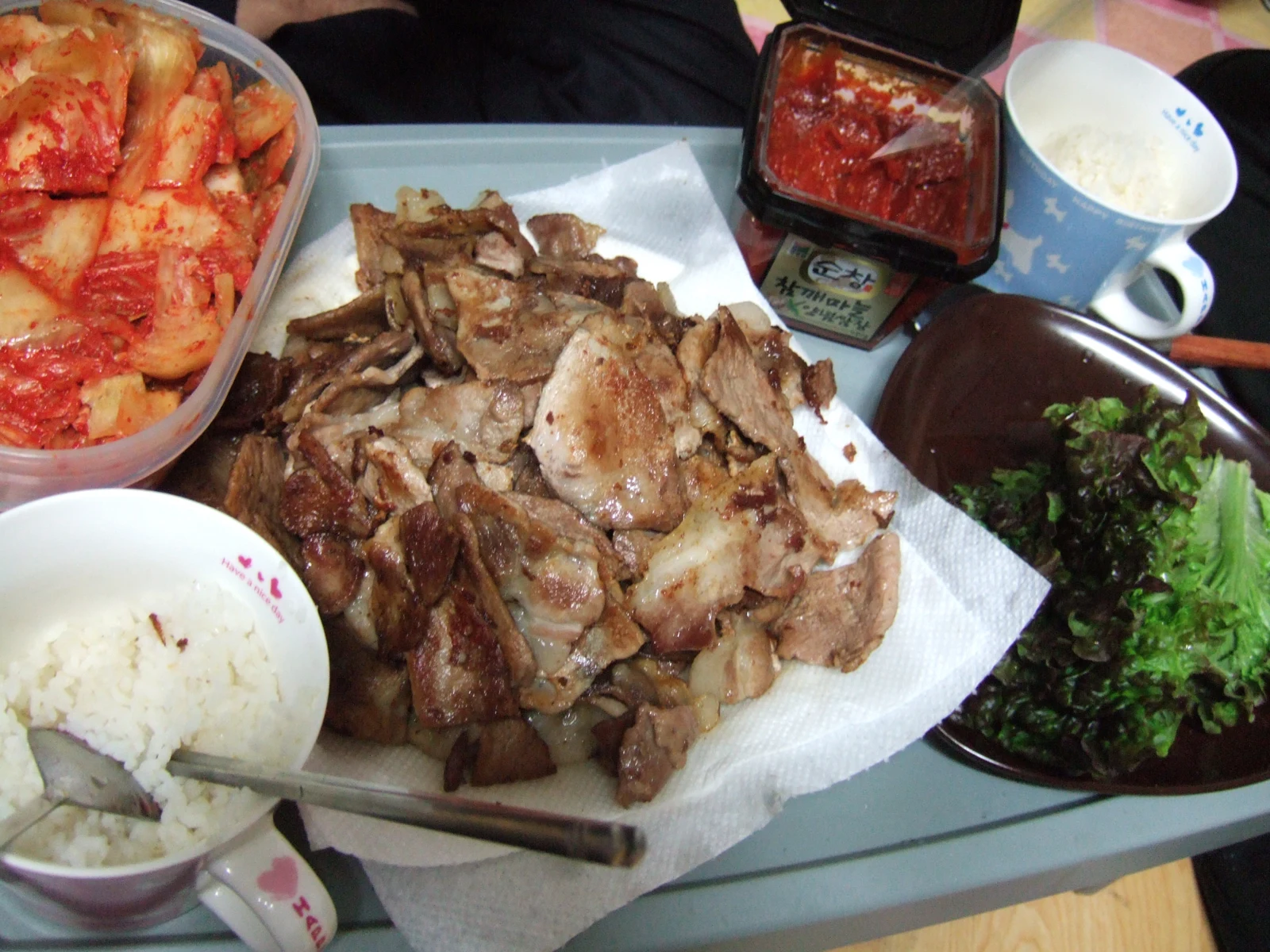 Grilled pork belly on a plate with rice, kimchi and leaves