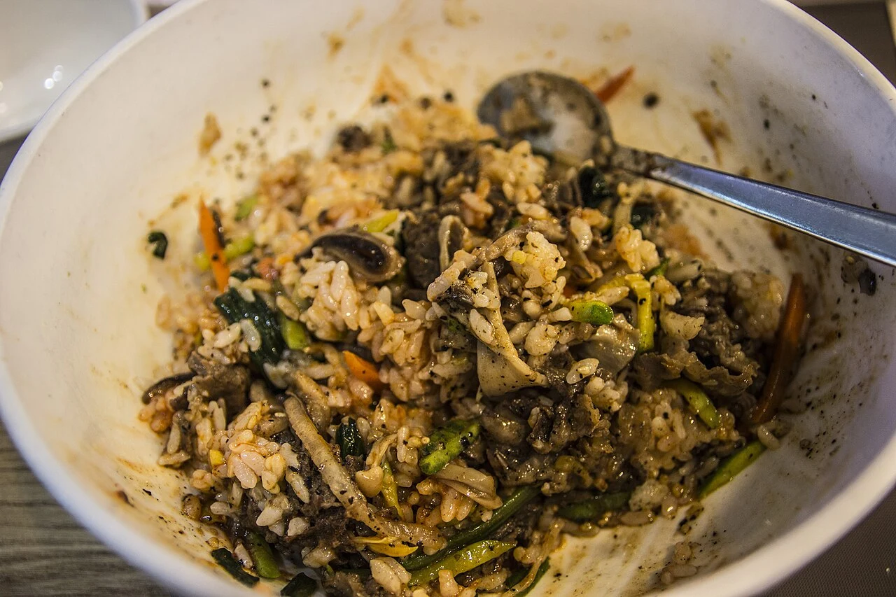 Rice mixed with vegetables and mushrooms in a white bowl