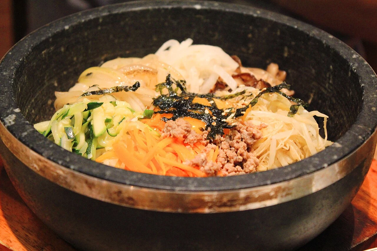 Vegetables and meat arranged separately in a dark stone bowl