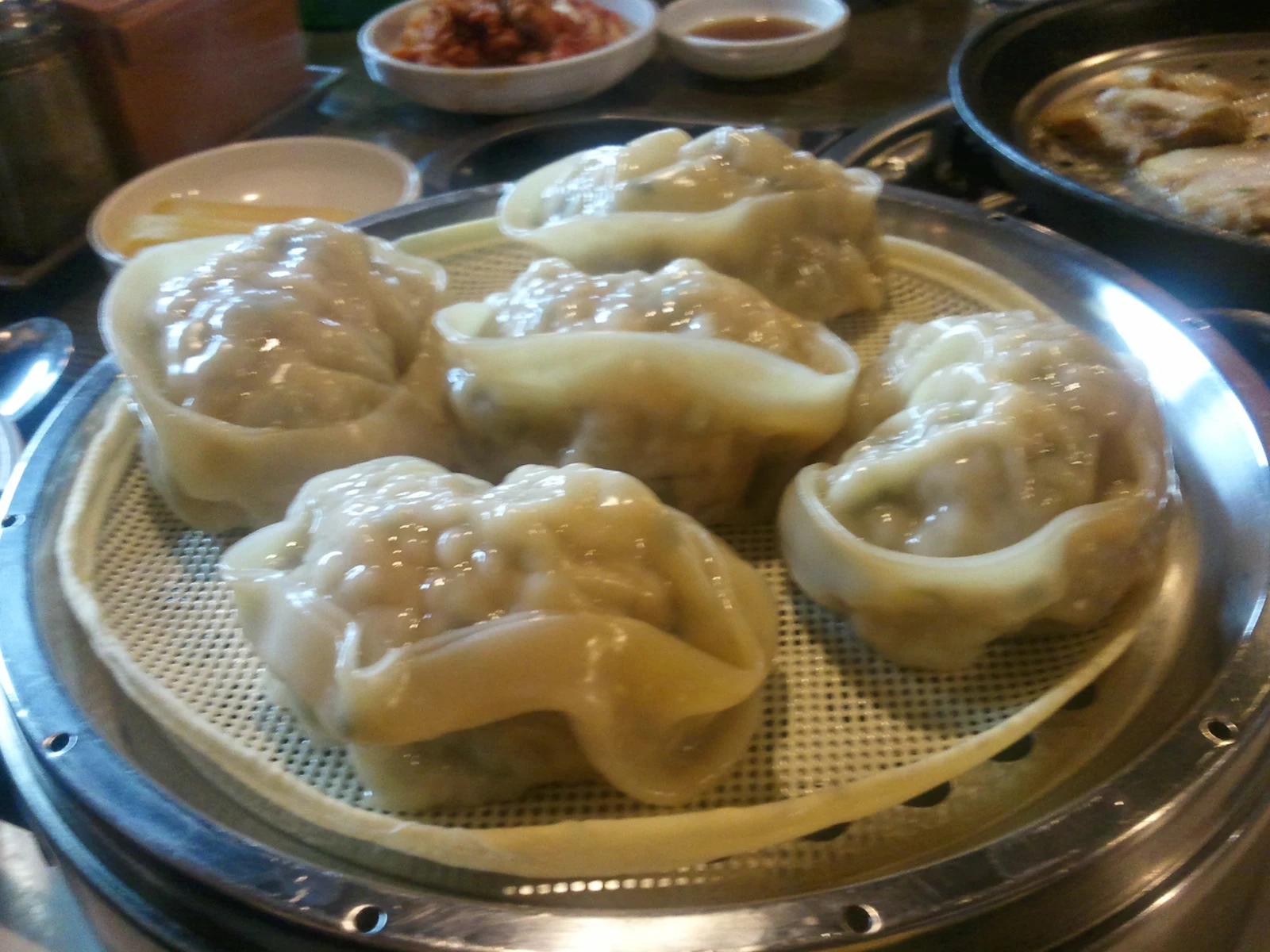 Round dumplings on a steaming tray with filling visible at the top