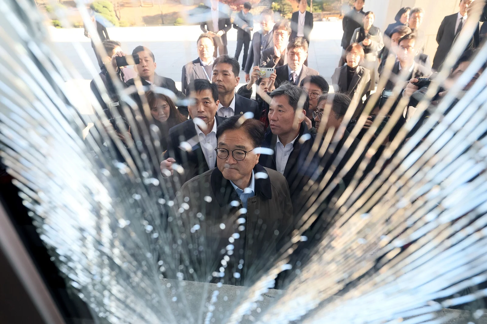 A damaged Assembly window and people inspecting it on December 4, 2024