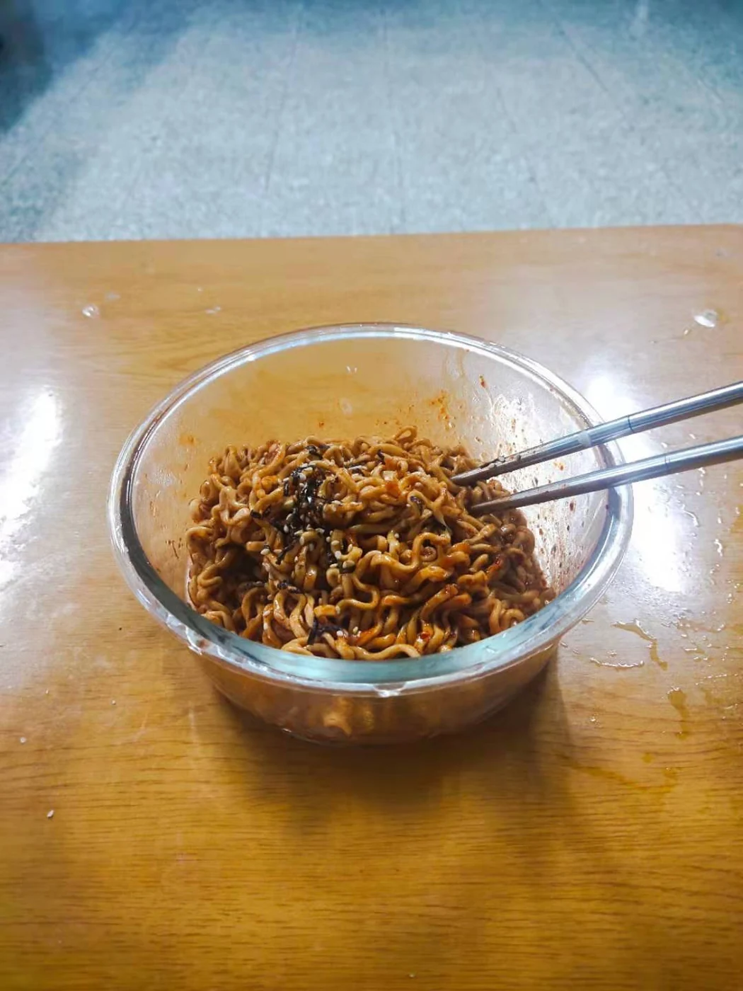 Cooked Buldak noodles in a glass bowl with metal chopsticks