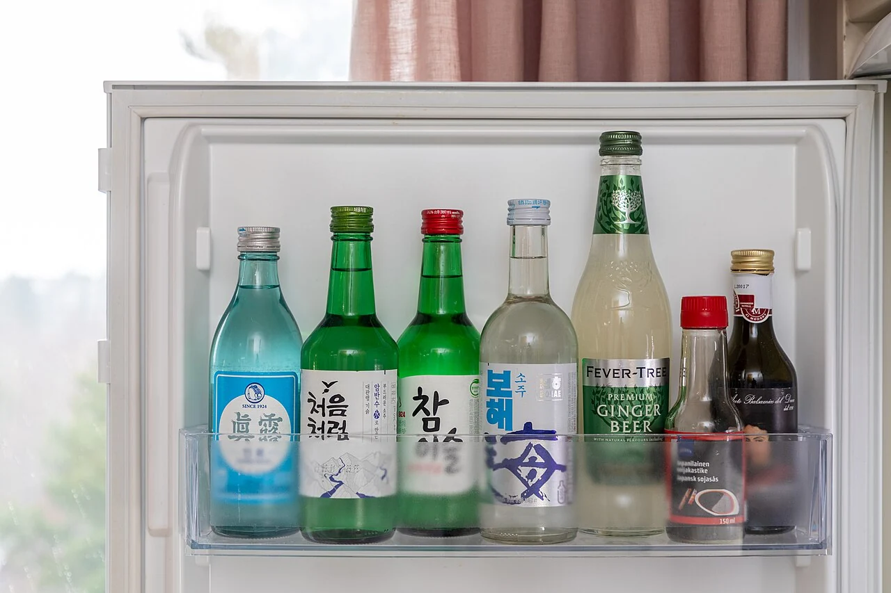 Soju beside other drinks and condiments in a refrigerator door