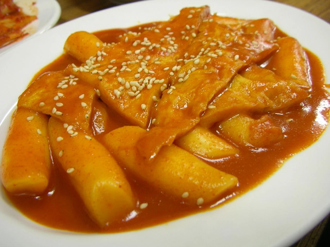 Red-sauced cakes, fish cake and sesame on a white plate